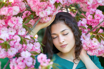 beautiful girl posing near sakura flowers as background, face closeup, springtime
