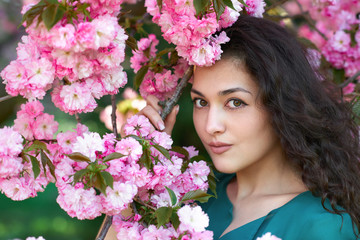 Fototapeta premium beautiful girl posing near pink sakura flowers as background, face closeup, spring landscape