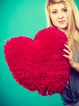 Happy woman holding red pillow in heart shape