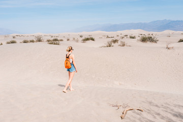 Girl with backpack walks on the desert in the lowest point on earth in Death valley, USA, West Coast
