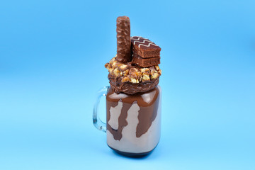Chocolate extreme milkshake with brownie cake, chocolate paste and sweets. Crazy freakshake food trend. Copy space
