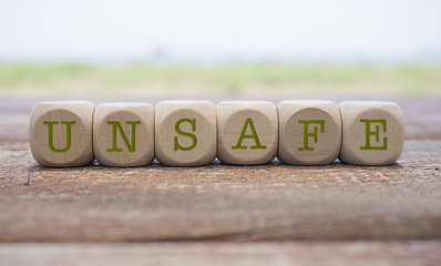 Unsafe word written on cube shape wooden blocks on wooden table.