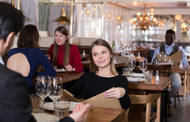 Girl with boyfriend choosing meal from menu