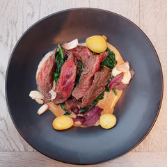 Medium rare fried steak in black plate