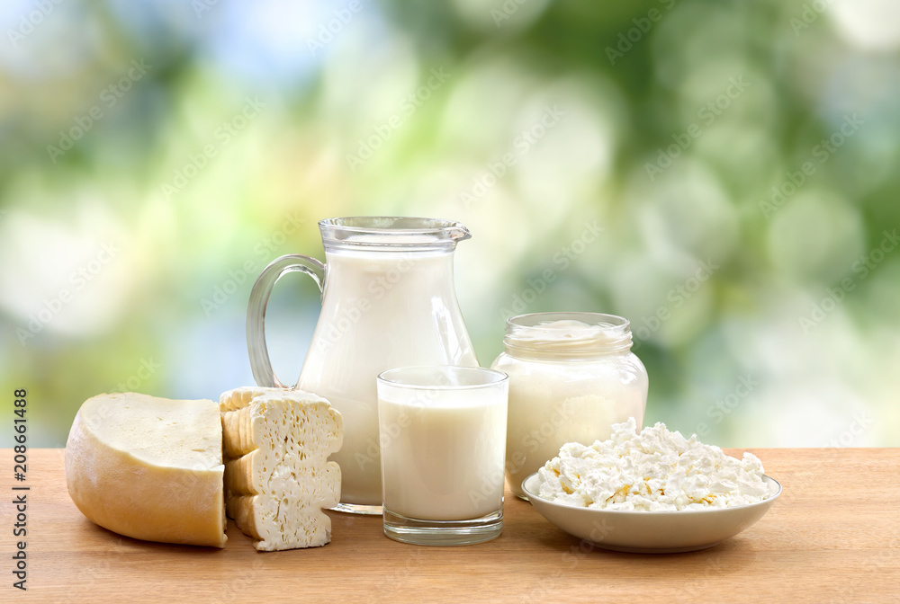 Wall mural milk, sour cream, cheese and cottage cheese on wooden table on defocused of natural background with 