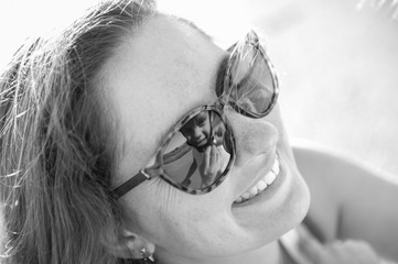 Obraz premium happy smiling woman helping little kid to wear helmet reflected in sunglasses