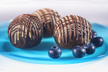 Chocolate cake and fresh blueberries on blue plate.
