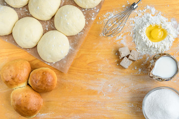 Baking background top view. Making sweet bun or bread dough. Cooking ingredients for pastry on wooden board with dough, egg, yeast, milk, flour. Culinary classes or recipe concept.