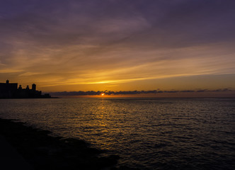 Sunset over Malecon and Atlantic Ocean with residential building in background - Havana, Cuba 
