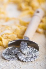 Pasta fresca casera cortada con un cortador de ruleta o rueda manual sobre la mesa de la cocina para la comida