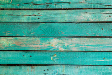 Texture of an old green fence made of wooden boards with knots and rusty nails