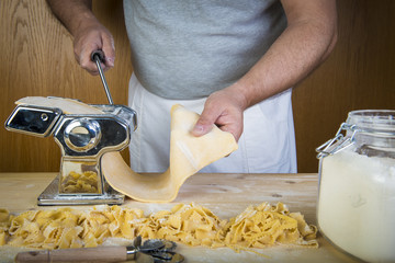 Chef de cocina italiano haciendo pasta fresca con una máquina sus manos para cocinar comida...
