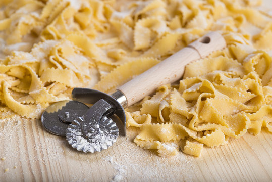 Pasta fresca casera cortada con un cortador de ruleta o rueda manual sobre la mesa de la cocina para la comida