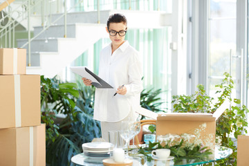 Serious busy attractive young female manager responsible for delivery checking goods and making...