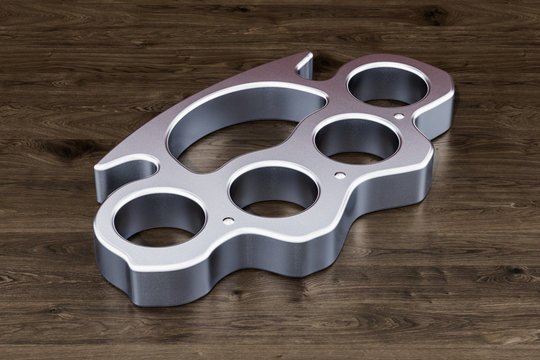 Brass knuckles on the wooden table, 3D rendering