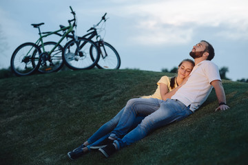 Romantic date of young couple outdoors. Young man and woman in love relaxing on green meadow. People and romance.