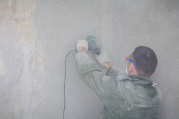 Professionality male contractor using professional angle grinder for cutting wall