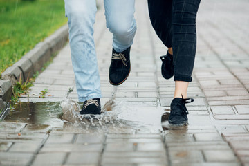 Young couple walking in the rain on puddles