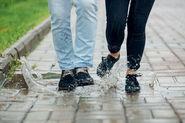Young couple walking in the rain on puddles - 208666660