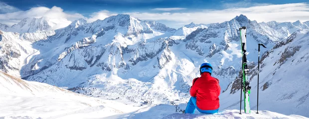 Photo sur Plexiglas Sports dhiver Young happy skier sitting on the top of mountains and enjoying view of Rhaetian Alps, Tonale pass, Italy, Europe
