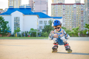 Little boy riding on rollers in the summer in the Park. Happy child in helmet learning to skate