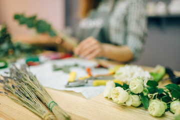 Female florist prepares bouquet of white roses