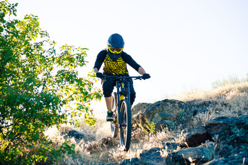 Naklejka na ściany i meble Cyclist Riding the Mountain Bike on the Summer Rocky Trail at the Evening. Extreme Sport and Enduro Cycling Concept.