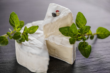 Brie type of cheese. Camembert cheese. Fresh Brie cheese and a slice on a wooden board with nuts, honey and leaves. Italian, French cheese.