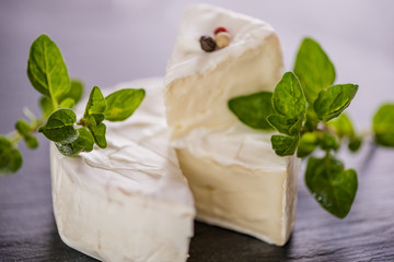 Brie type of cheese. Camembert cheese. Fresh Brie cheese and a slice on a wooden board with nuts, honey and leaves. Italian, French cheese.