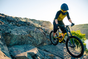 Fototapeta premium Cyclist Riding the Mountain Bike on the Summer Rocky Trail at the Evening. Extreme Sport and Enduro Cycling Concept.