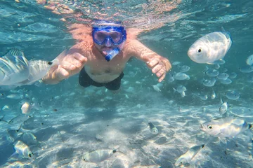 Fototapeten Young man snorkeling in underwater coral reef on tropical island. © Eva Bocek
