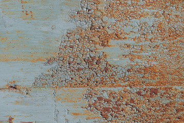painted iron surface with a large rusty and metal corrosion, chipped paint, old background with peeling and cracking paint, texture