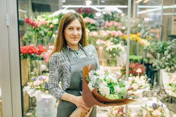 Florist in apron with fresh bouquet in flower shop