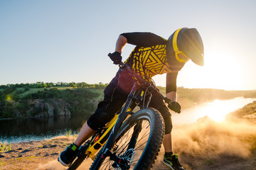 Cyclist Riding the Mountain Bike on the Summer Rocky Trail at the Evening. Extreme Sport and Enduro Cycling Concept.