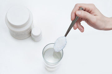Powder absorbent on a spoon over a glass with water. Close-up. Top view