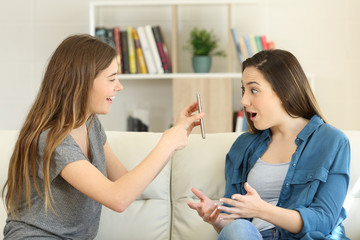 Girl showing smart phone content to an amazed friend