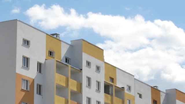 Building skyscraper on a background of blue sky with white clouds. Time laps