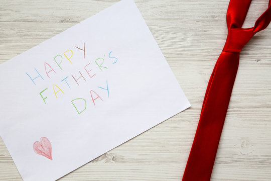 Happy Father's Day inscription with red tie on white wooden background.
