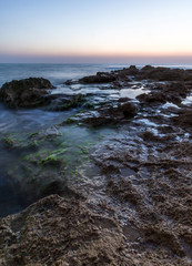 Twilight at a rocky beach full of scum