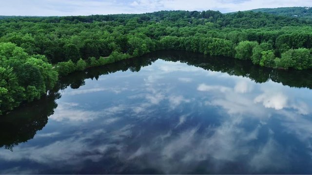 Drone footage of a slow panning arieal view of Scarlet Lake with cloud reflections on still water.