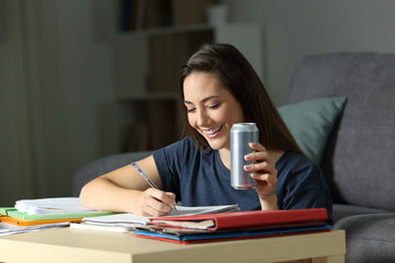 Happy woman studying holding energy drink
