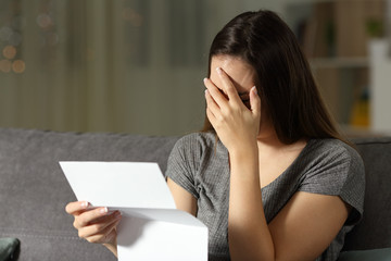 Sad woman reading a letter in the dark