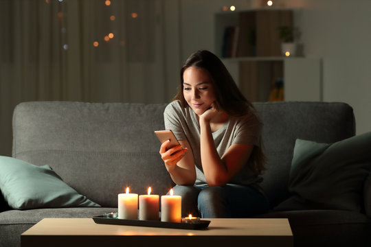 Relaxed girl using phone in the night with candle lights