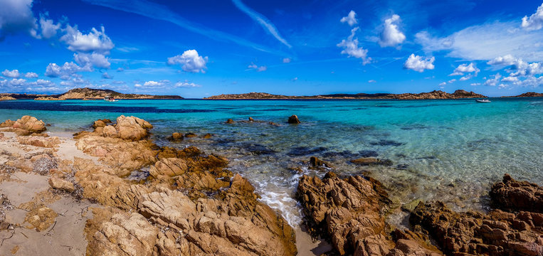 Panoramic view of a rocky beach with clear colorful water
