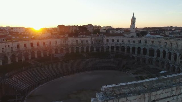 Aerial drone shot of a rising sun over an ancient amphitheater in Pula, idyllic morning setting in Croatia