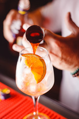 The barman pours Aperol into the cocktail of Aperol Spritz close up