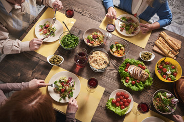 Top view of healthy food served for household members. They are sitting and eating together in...