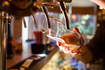 The barman pours light unfiltered beer from the tap