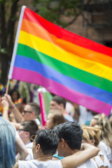 Participants wave rainbows flags in the annual Pride Parade as it passes past a couple embracing in...