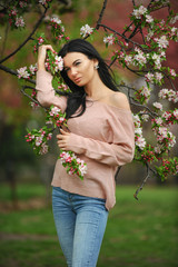 Fashion outdoor photo of beautiful charming woman posing in spring blossom garden.